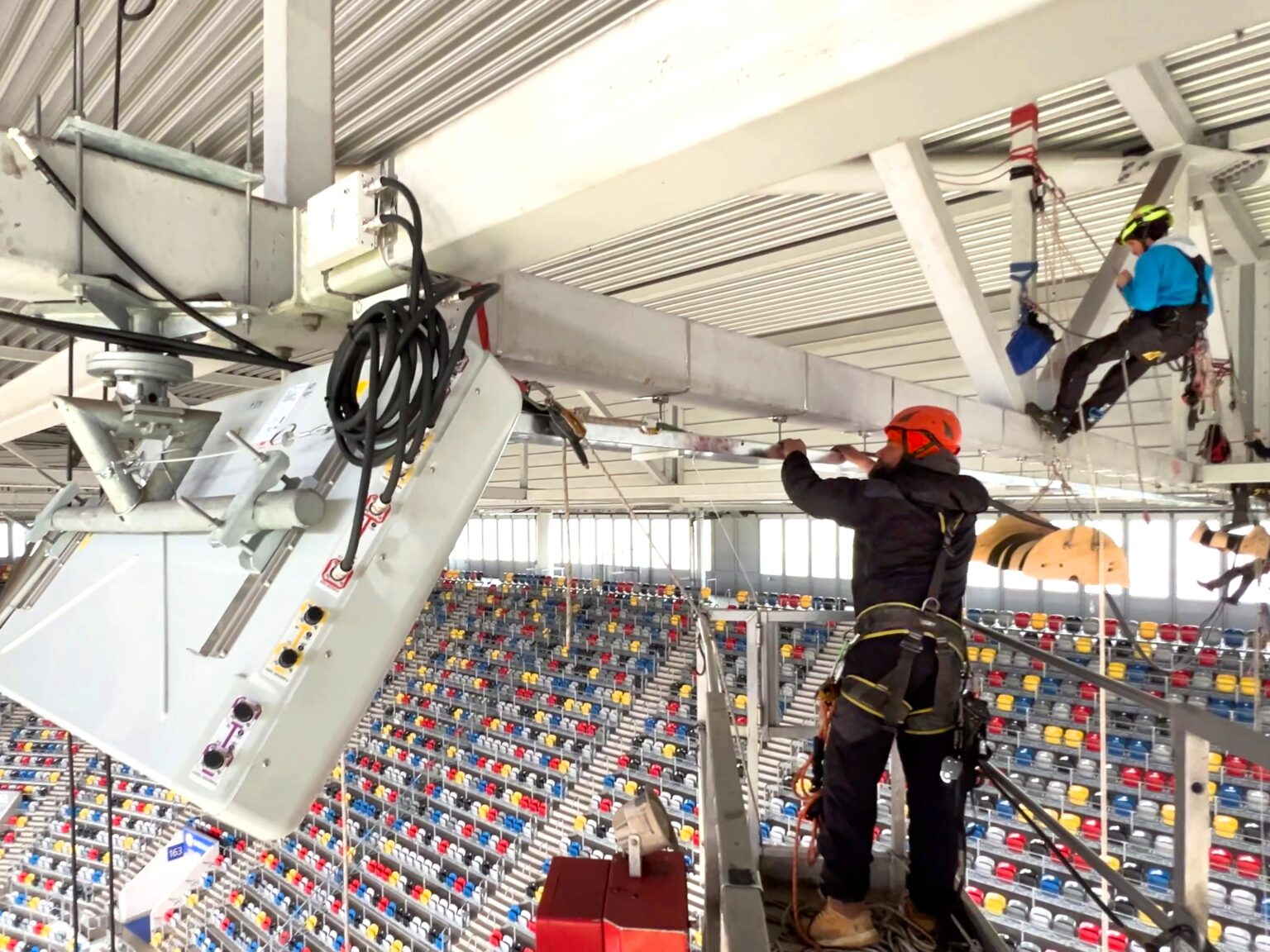 Symbolbild für Handyempfang zur Fußball-EM: Technikpersonal installiert Mobilfunktechnik unter einem Sportstadiondach
