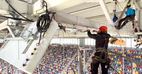 Symbolbild für Handyempfang zur Fußball-EM: Technikpersonal installiert Mobilfunktechnik unter einem Sportstadiondach