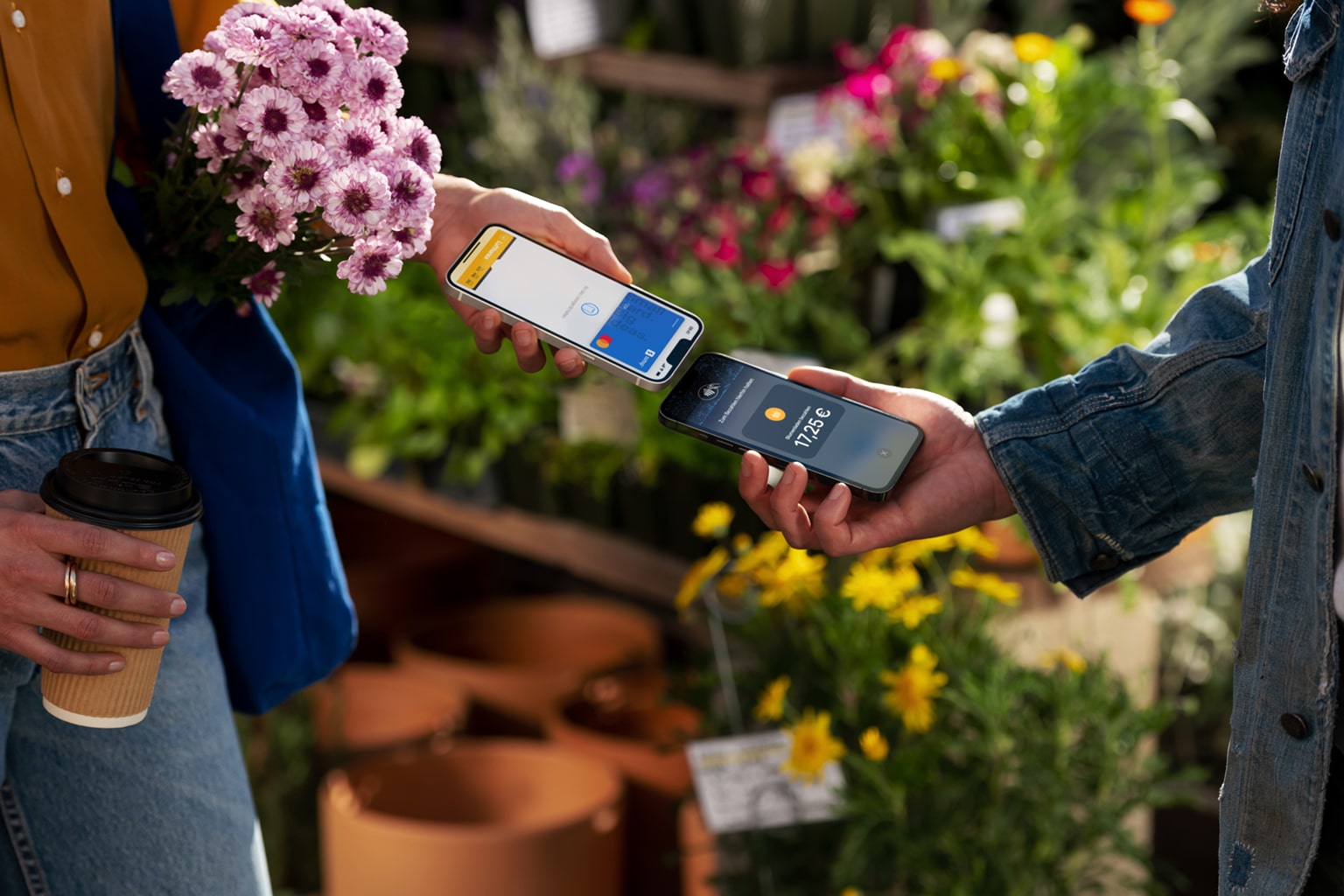 Zwei Menschen am Gemüsestand halten iPhones gegeneinander, um mit Apple Tap to Pay einen Einkauf zu bezahlen