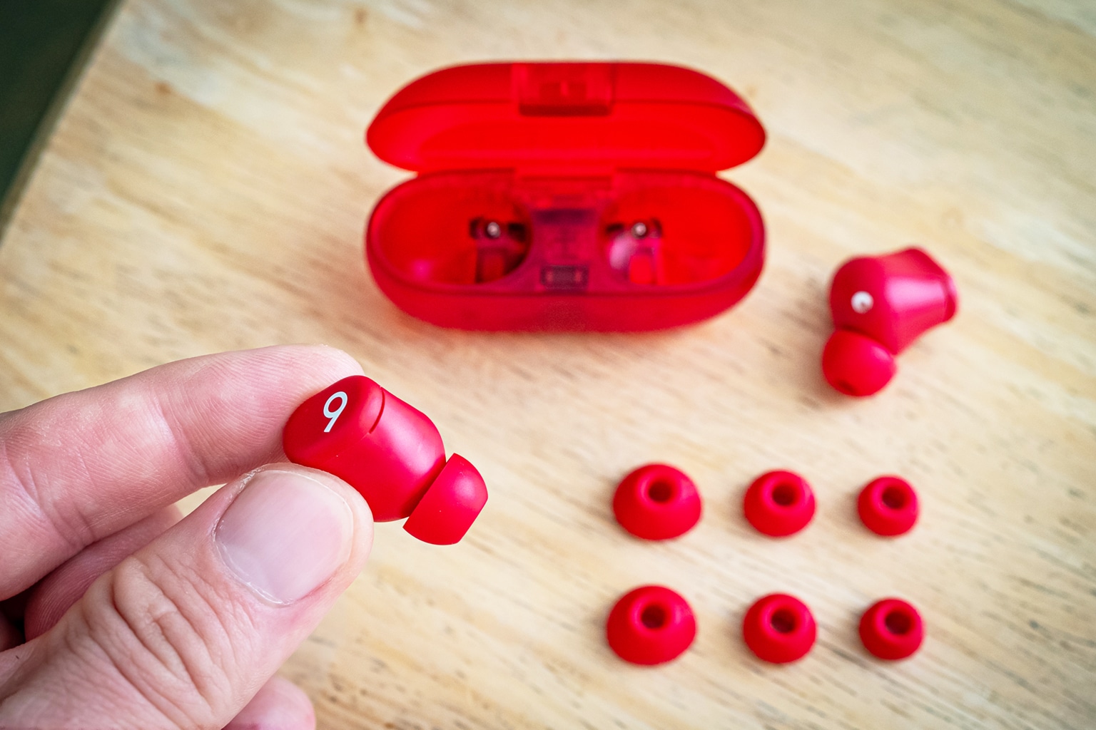 Rote Beats Solo Buds aus dem Case genommen, umringt von Ohrpassstücken in verschiedenen Größen
