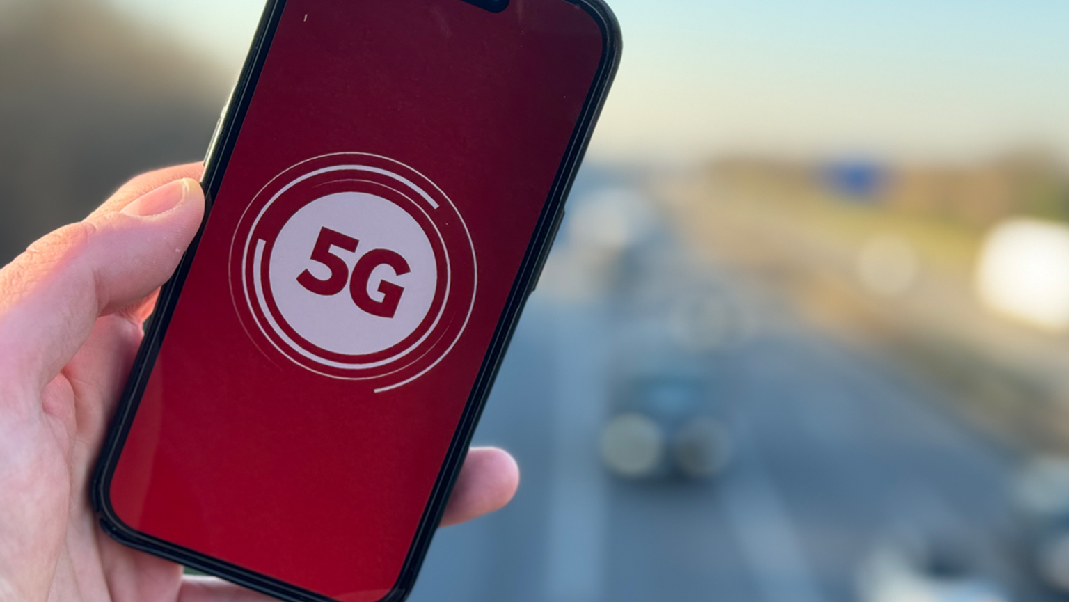 5G-Symbol auf Hintergrund in Vodafone-Rot auf Display eines Smartphones, das in einer Hand gehalten wird