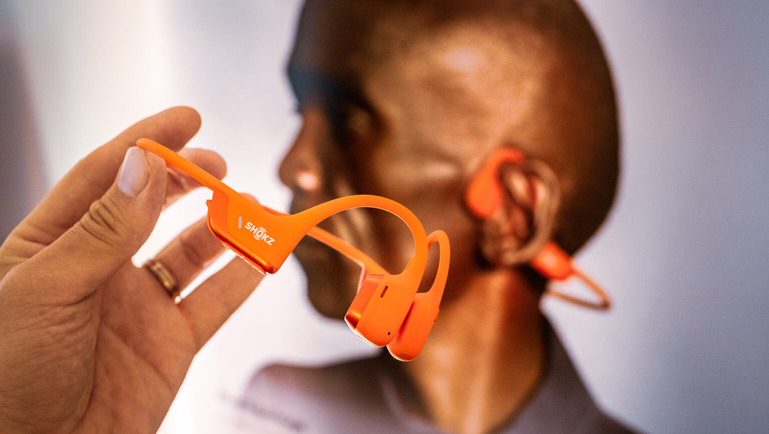 Shokz OpenRun Pro 2 in Orange in der Hand gehalten