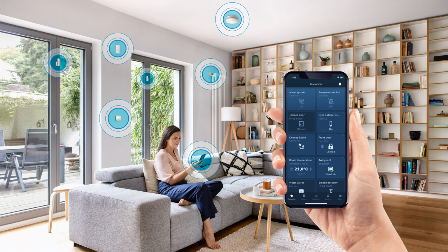 Frau sitzt im Wohnzimmer, davor ein Handy mit Bosch Smart Home App Ansicht