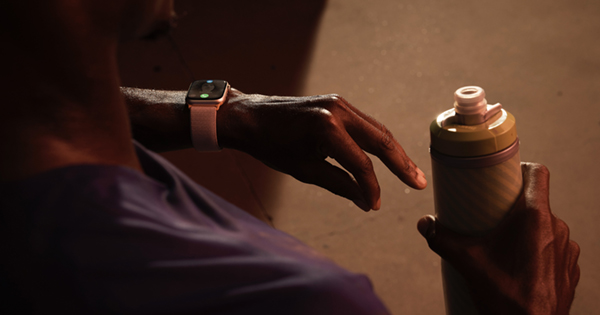 Apple Watch an der einen Hand, Trinkflasche in der anderen Hand.