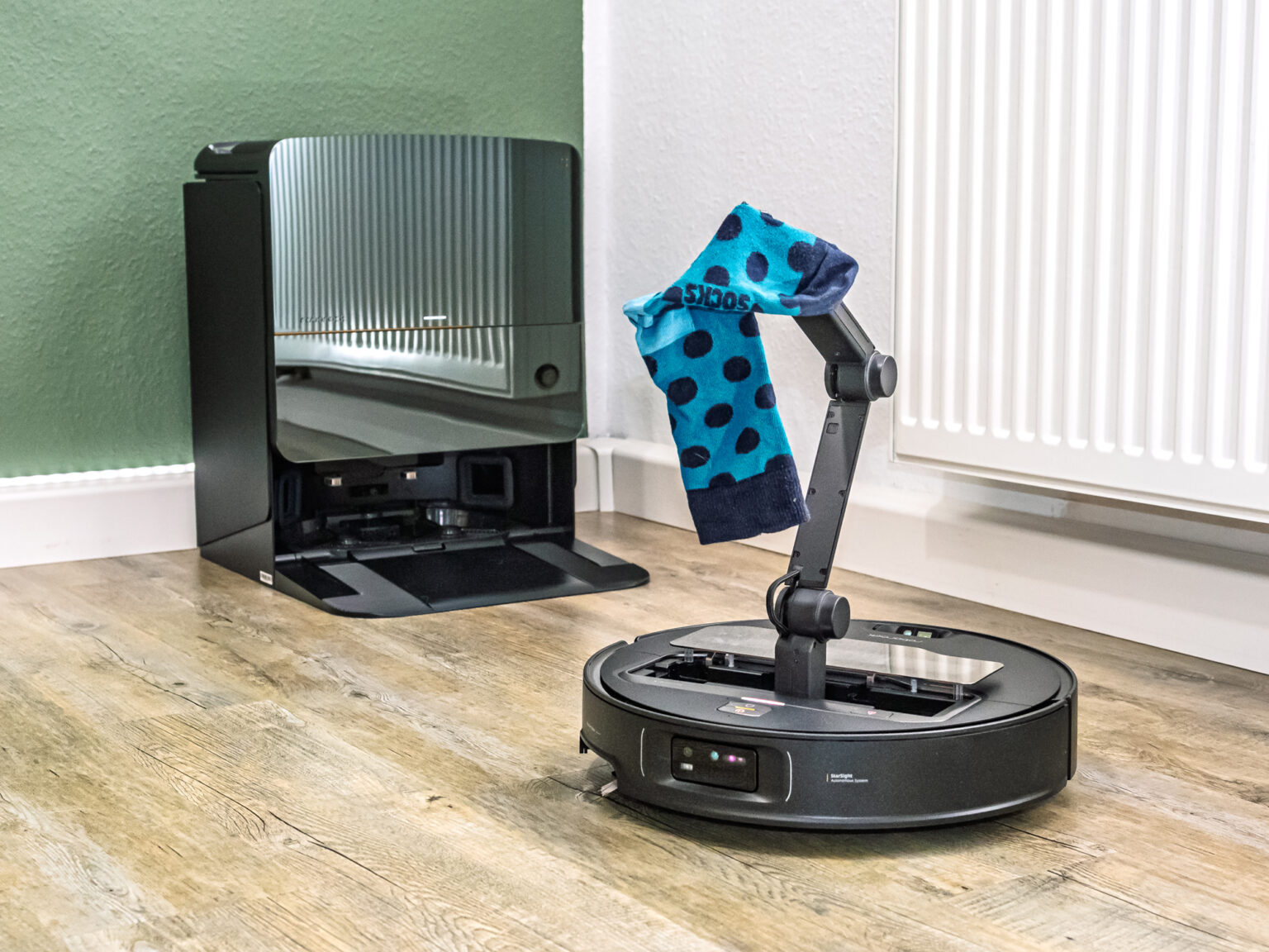 Greifarm des Roborock Saros Z70 hebt Socke vor Basisstation an