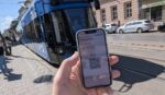 Revolut-App mit ÖPNV-QR-Code vor einer blauen Straßenbahn gehalten.