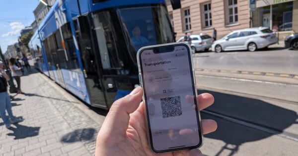 Revolut-App mit ÖPNV-QR-Code vor einer blauen Straßenbahn gehalten.
