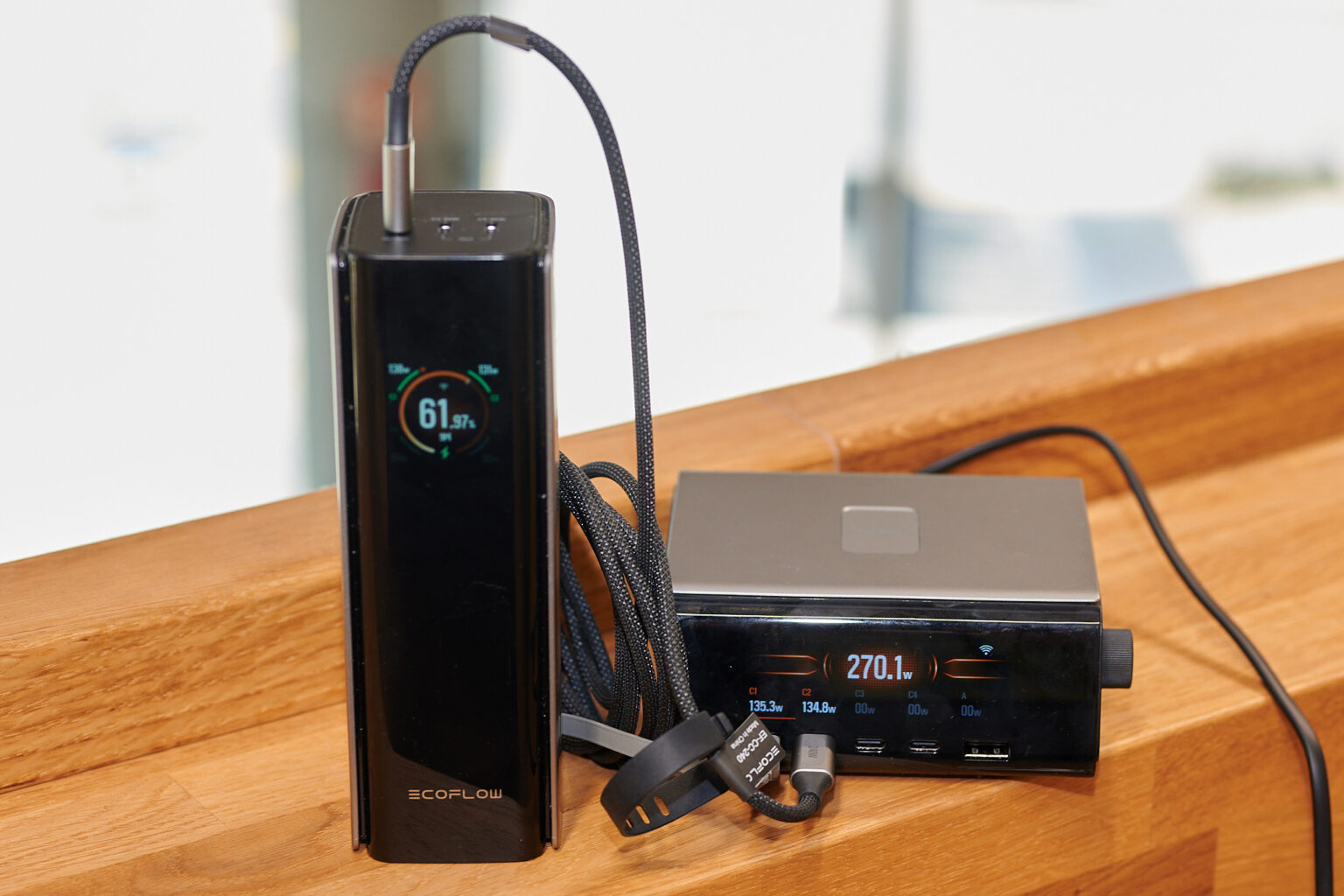 Powerbank steht neben dem Tischladegerät. zwei USB-Kabel versorgen die Powerbank. Charger zeigt 130+-Watt auf dem Display an.