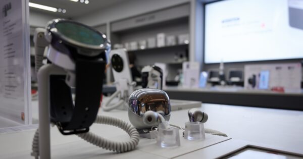 Blick in den Xiaomi-Store im Hintergrund mit Nahaufnahme auf eine Smartwatch und ein Ohrhörer-Case (freigestellt).