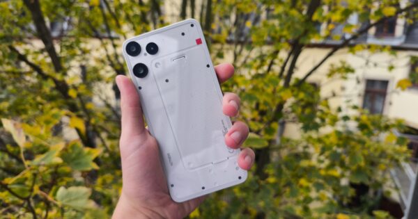 Nothing Phone 3a Lite vor Bäumen draußen in der Hand, Rückseite in Weiß mit Kamera-Linsen