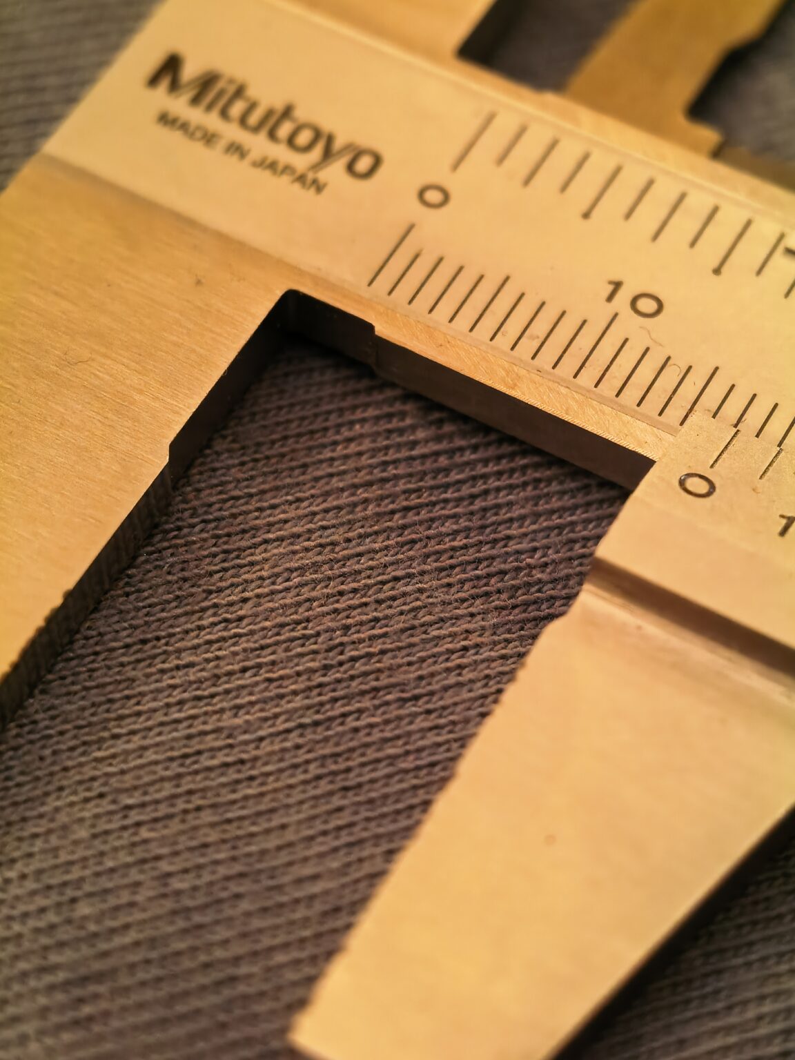 Blick auf Stoff mit einem Messschieber dadrüber.