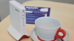 Fritzbox neben einer Tasse für einen Größenvergleich.
