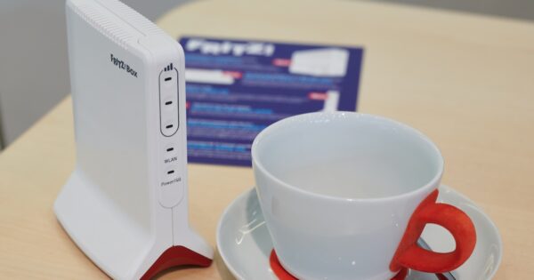 Fritzbox neben einer Tasse für einen Größenvergleich.