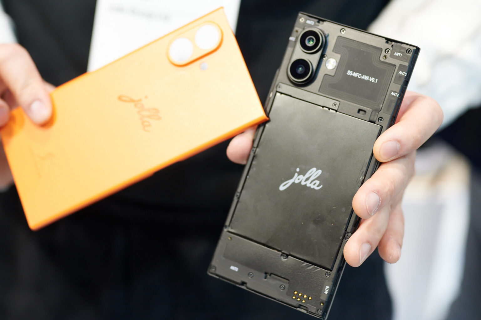 Abgenommenes Rückcover in einer Hand. Handy mit erreichbarem Akku in der anderen.