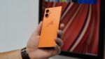Jolla Phone in Orange in der Hand gehalten. Rückseite, mit Schriftzug.