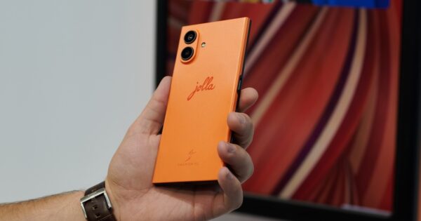 Jolla Phone in Orange in der Hand gehalten. Rückseite, mit Schriftzug.