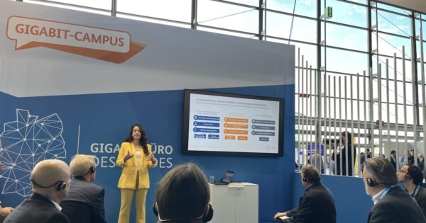 Vortragssituation mit Bildschirm, Folien und Zuschauern.