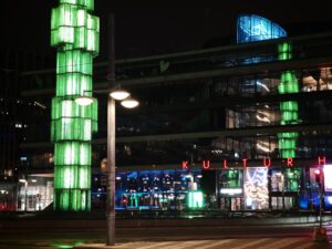Blick auf ein KAufhaus und Kunstwerk am Abend.